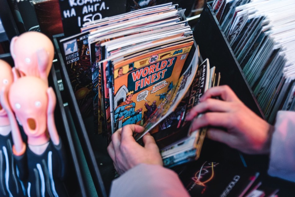 Illustrative photograph of hands browsing comic books in a shop